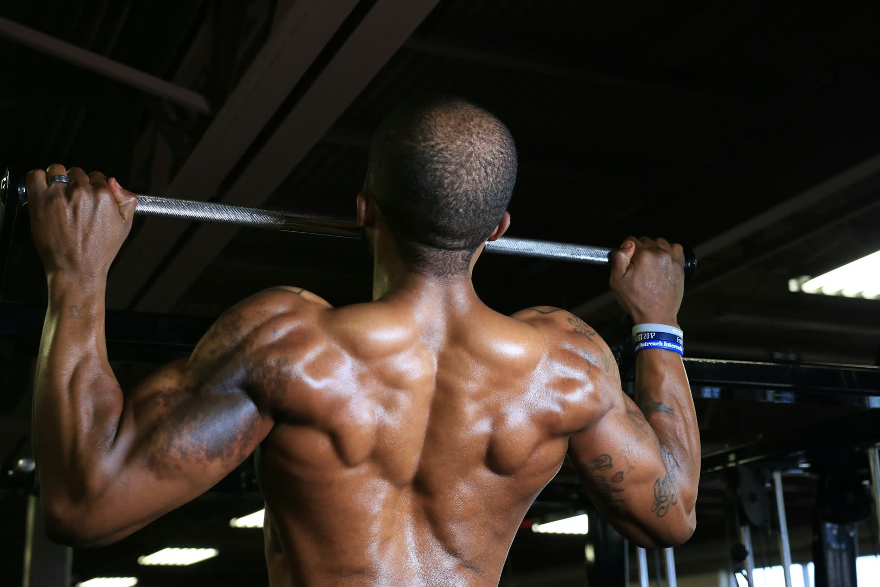 Athlete doing pull-ups in a dark gym